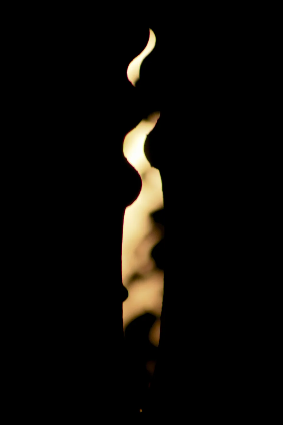 A single candle flame burning against pure black.